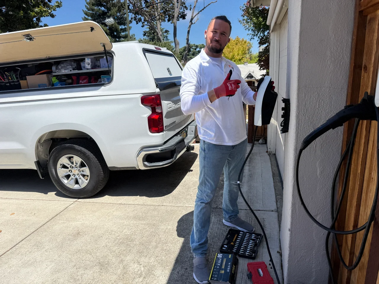 Technician holding a Tesla charging unit beside its wall mount